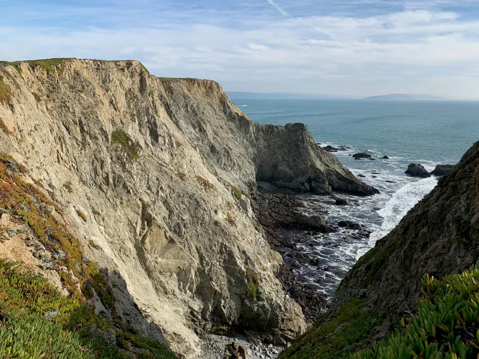Sheer granite sea cliff dropping to surf on Sonoma coast