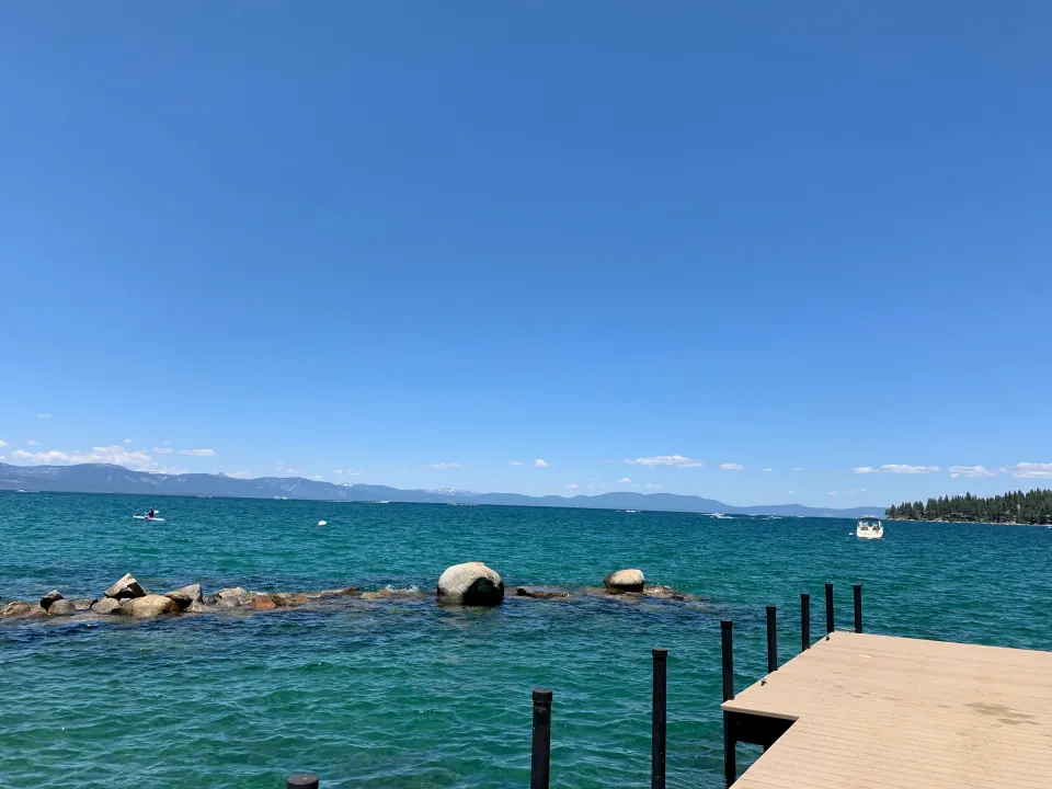 Clear turquoise Lake Tahoe water over granite boulders, distant mountains