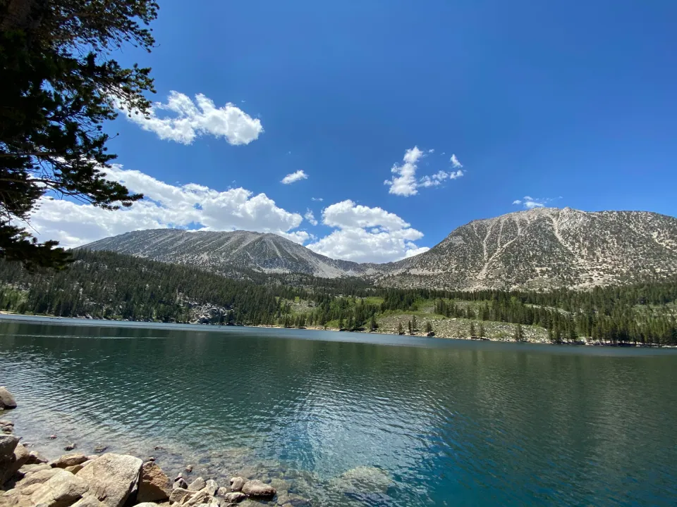 Turquoise alpine lake below Sierra peaks and summer clouds