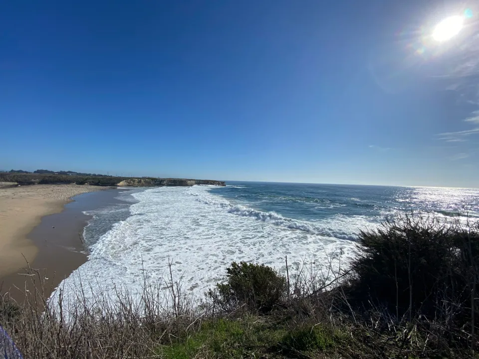 White surf rolling onto a sandy beach below the bluffs