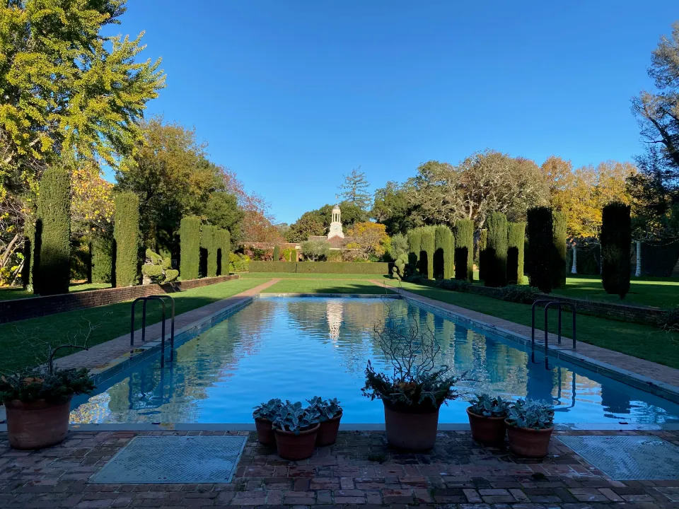 Formal garden reflecting pool lined with clipped yews, autumn light