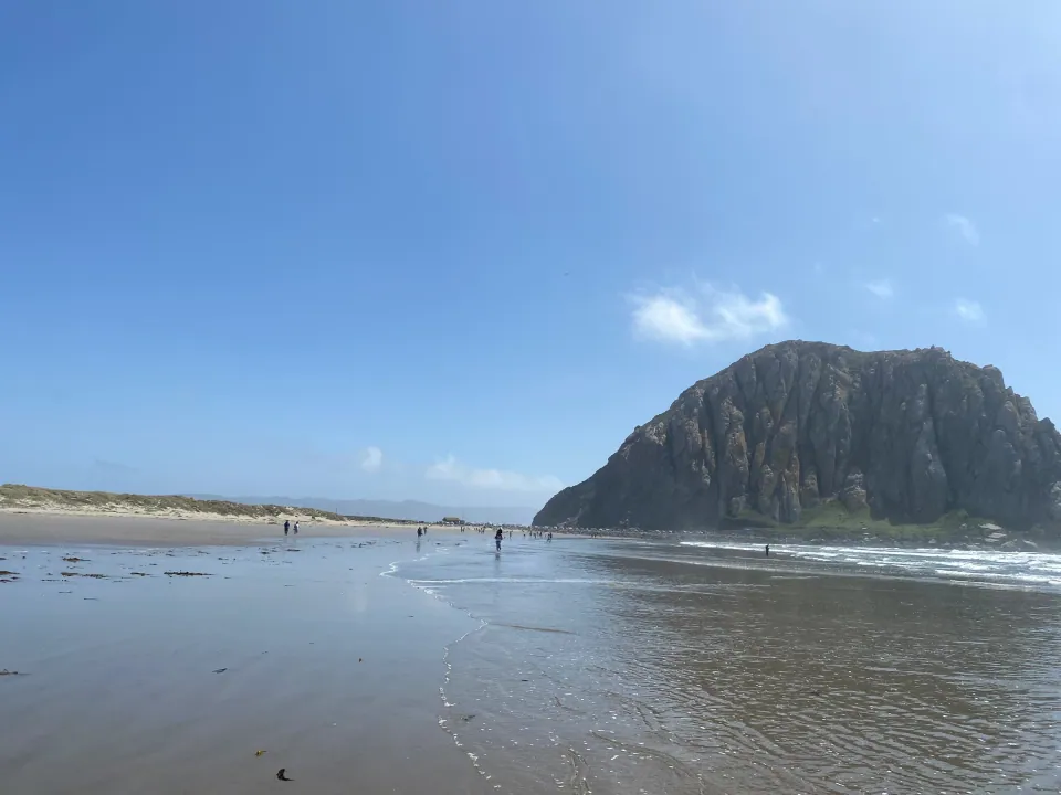 Morro Rock from the wet sand beach at low tide, blue sky