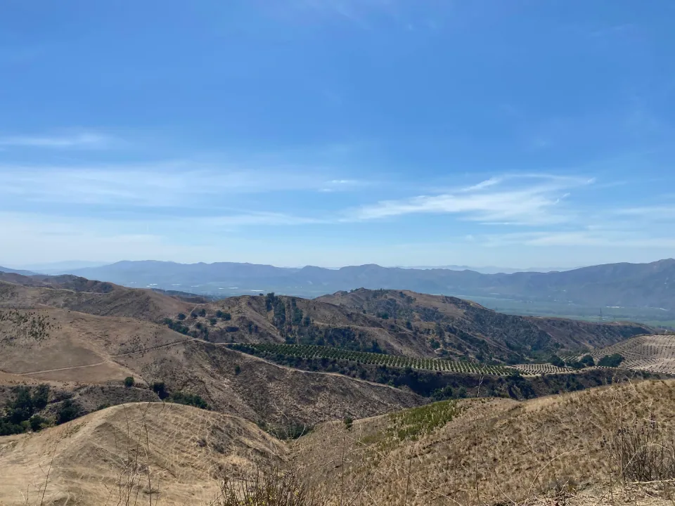 Layered dry ridges and distant mountains under clear sky