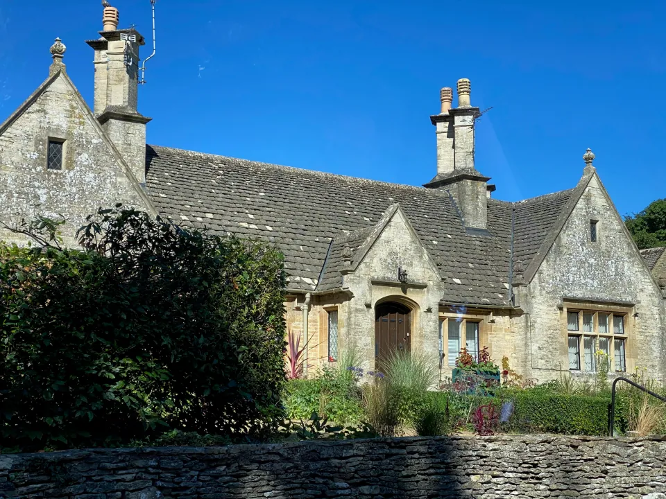 Cotswold stone gabled house under bright blue sky