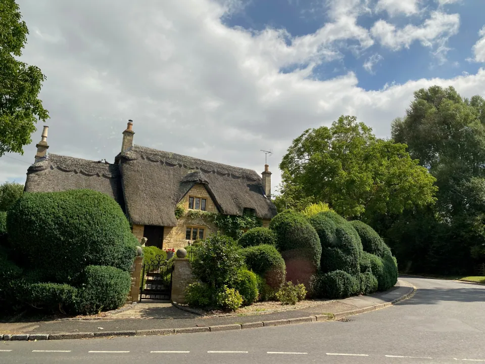 Cotswold thatched cottage with clipped hedges and garden