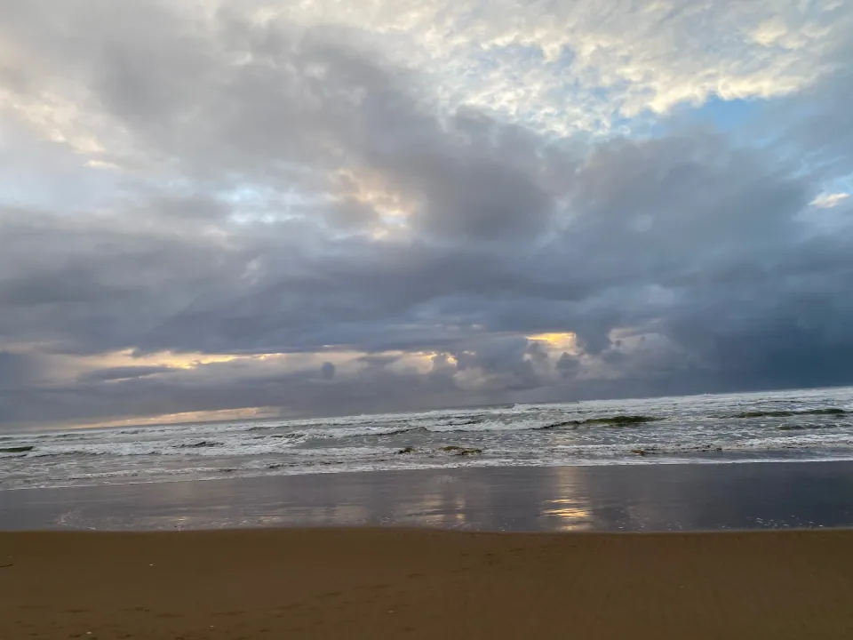 Dramatic storm clouds and light reflecting on wet beach
