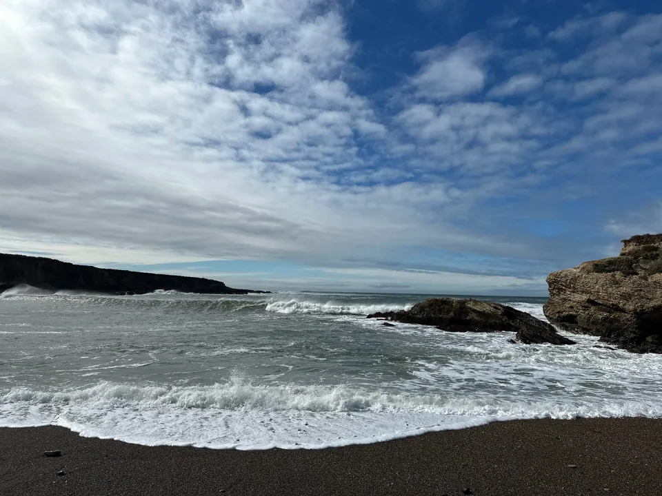 Waves breaking on dark rocks under moody clouds