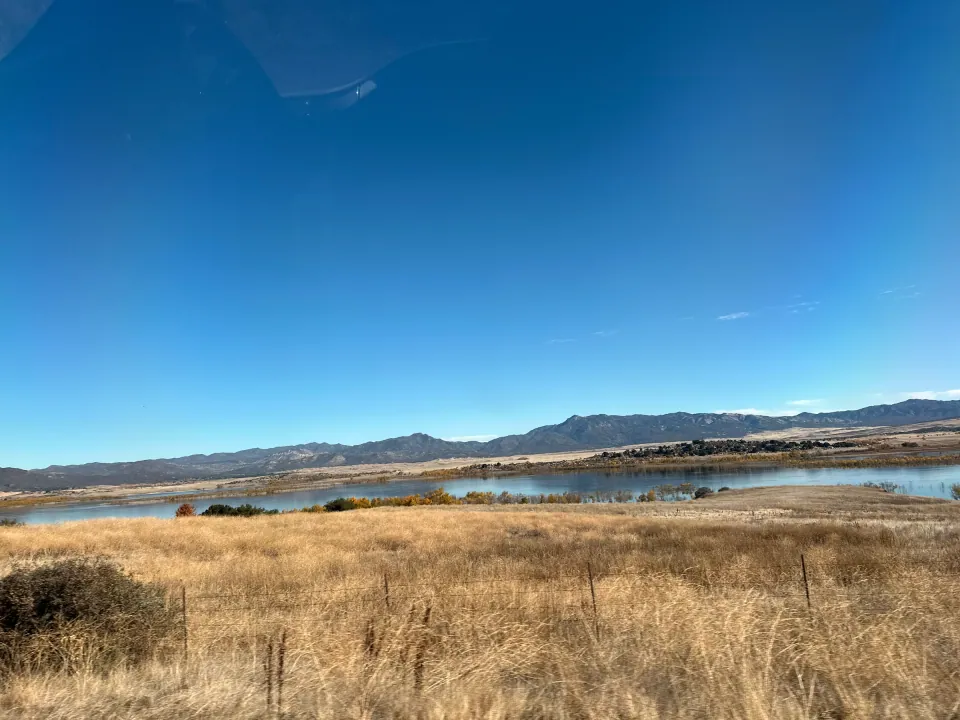 Golden grassland and lake beneath distant blue mountain range