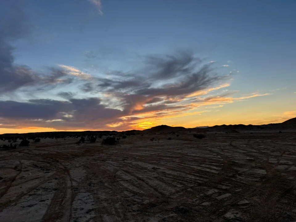 Desert flats at dusk under streaked orange and blue clouds