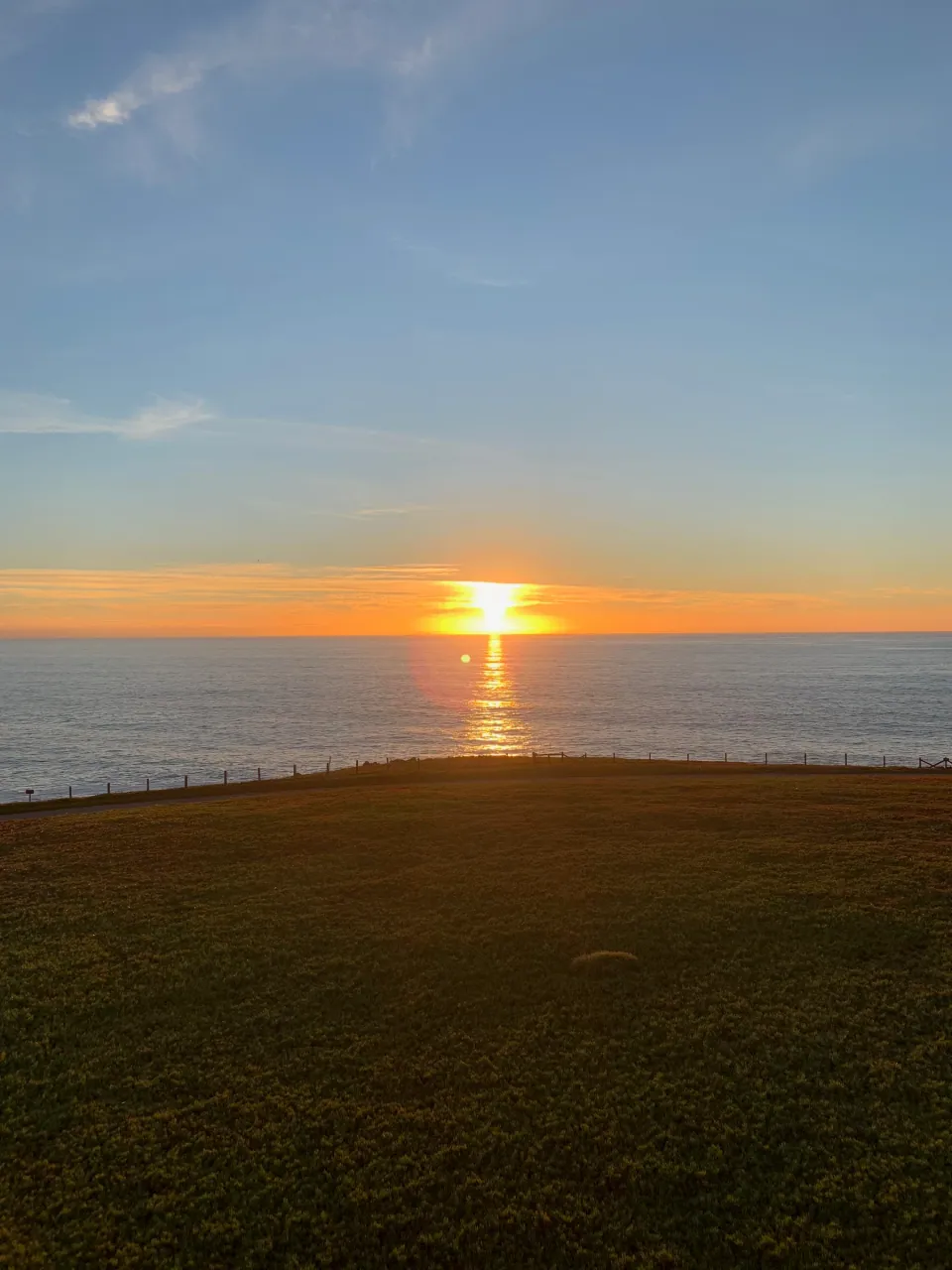 Sun setting into the ocean beyond a dark headland