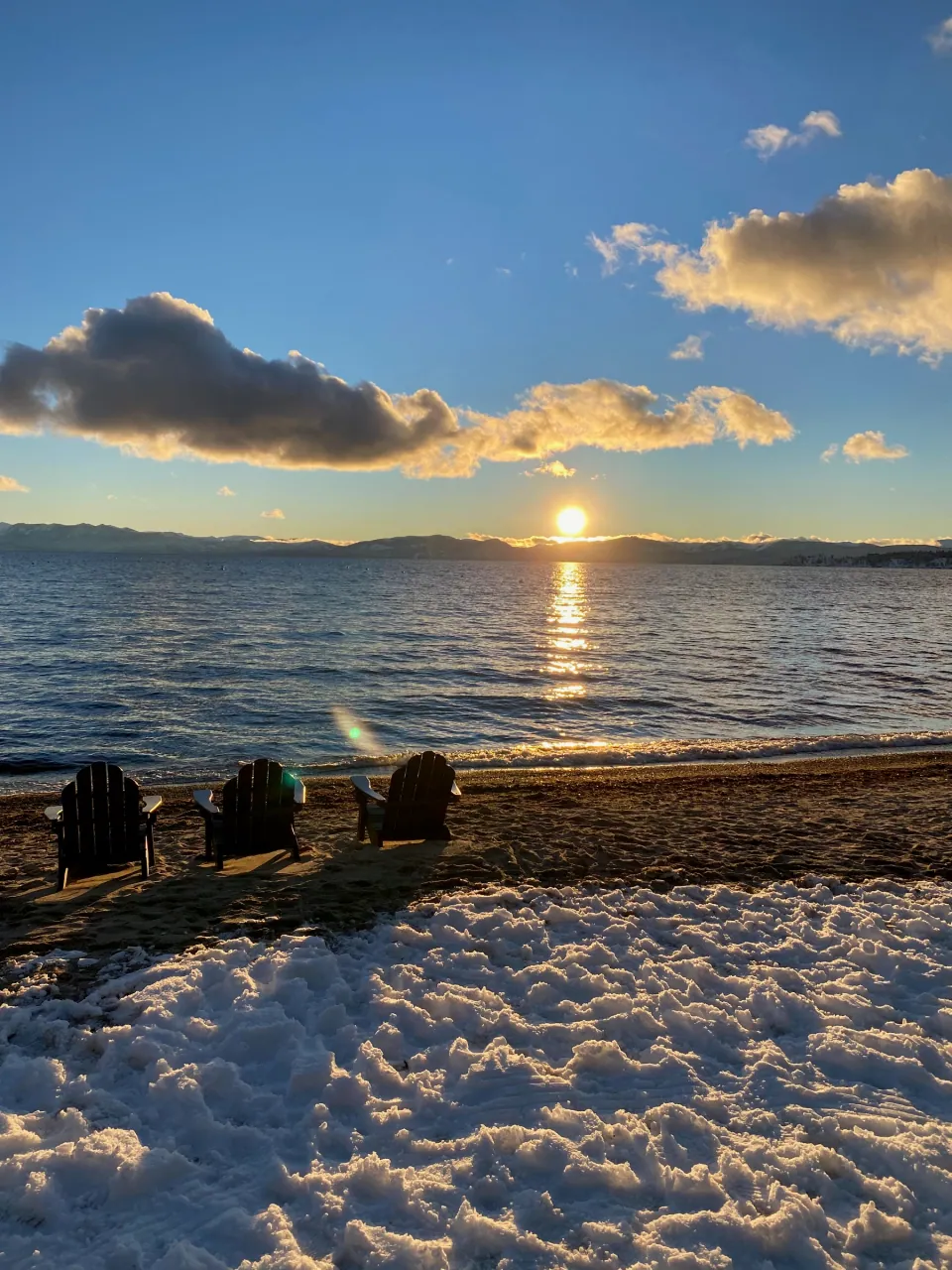 Sun setting over the lake beyond chairs on the beach