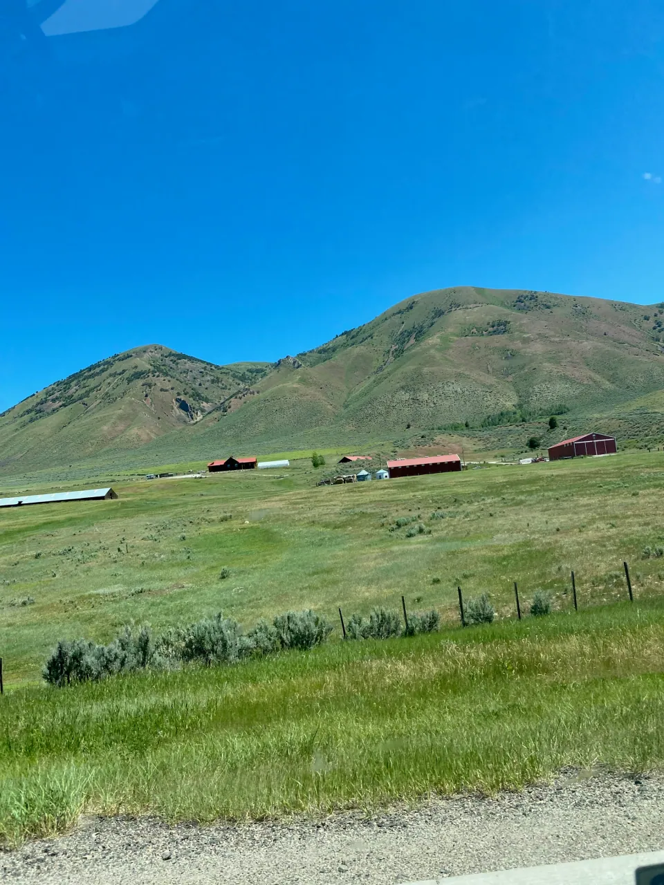 Red barns in a green valley below the mountains