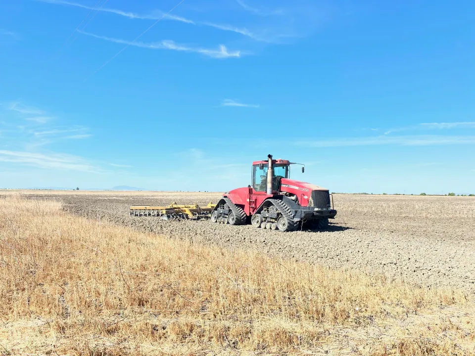 Red track tractor working a stubble field