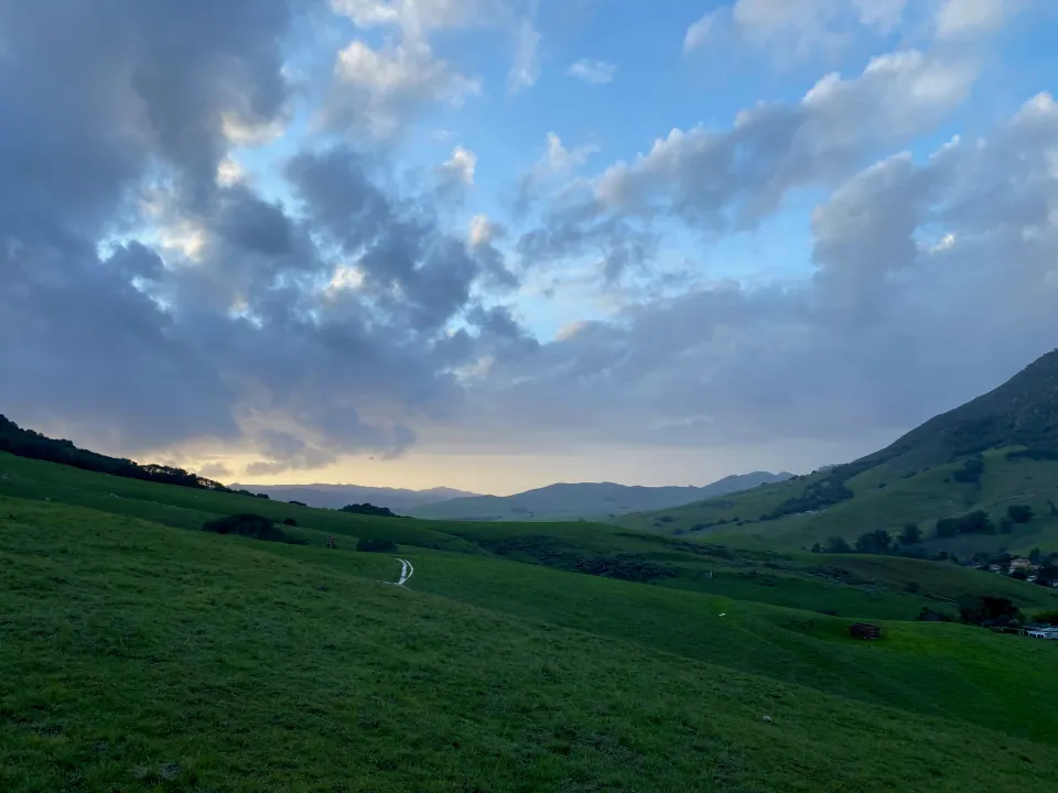Storm clouds breaking over a green valley at dusk