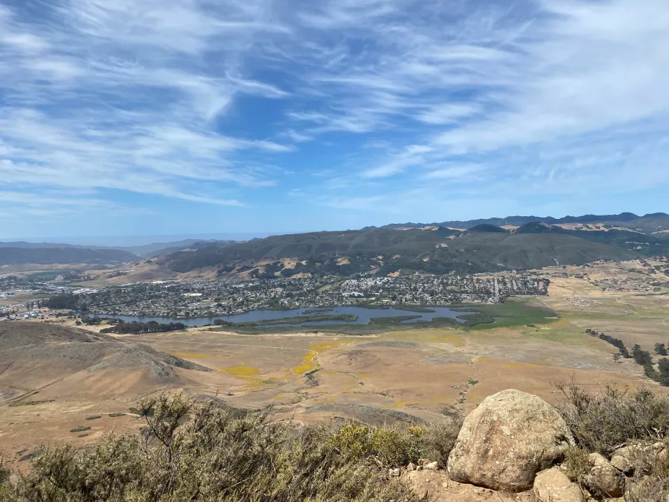 A lake and the town spread below the rocks of a hilltop