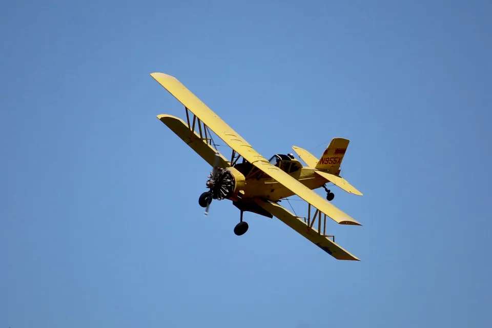 Yellow crop duster banking against a blue sky