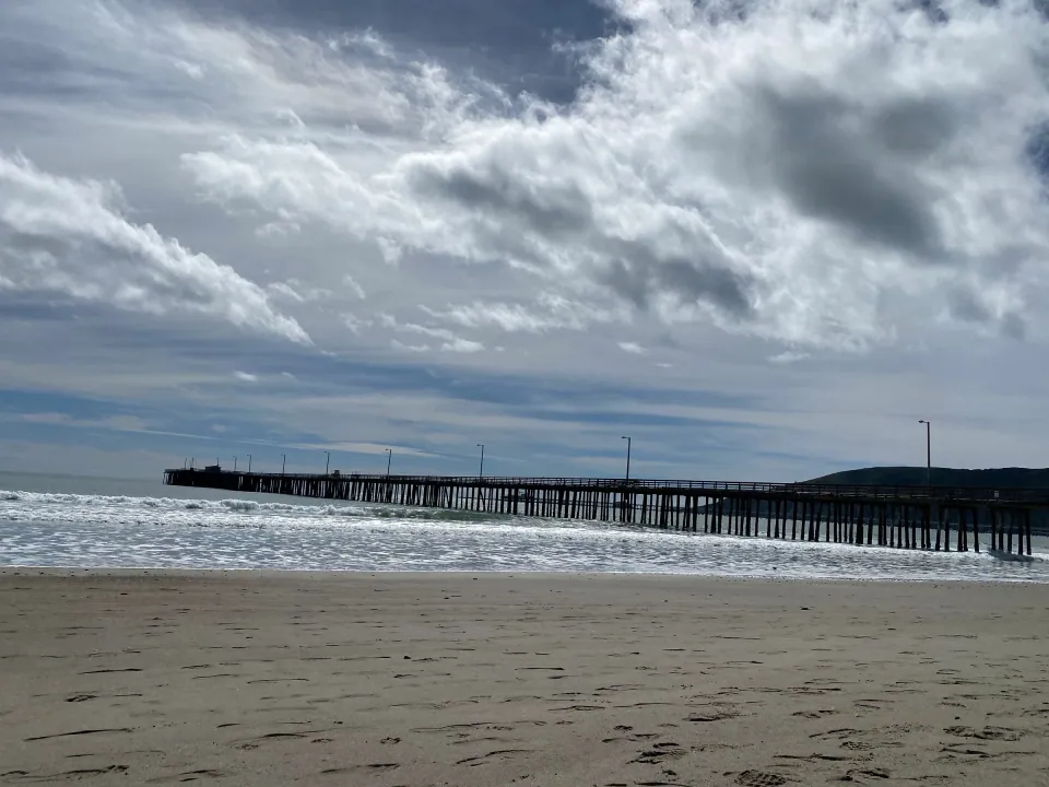 Pier and wet sand under a sky of moving clouds