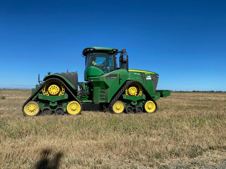 Green track tractor parked in a dry field