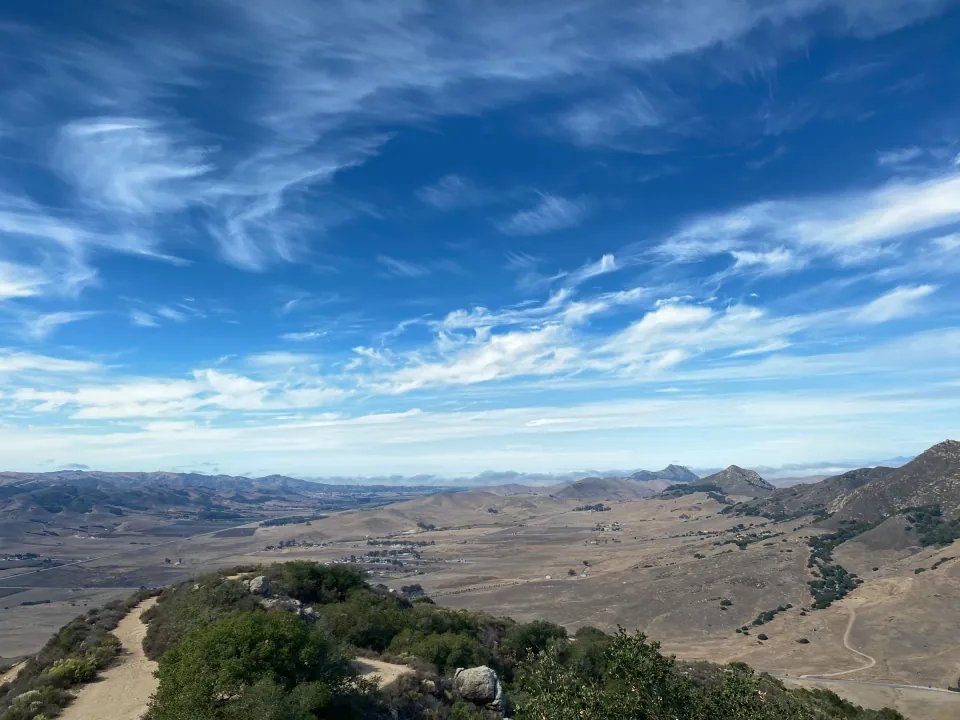 Trail along a ridge with the valley and peaks below