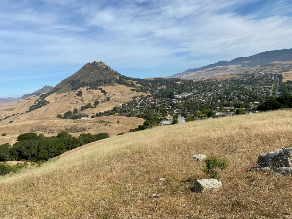 Volcanic peak above dry summer grass and the town