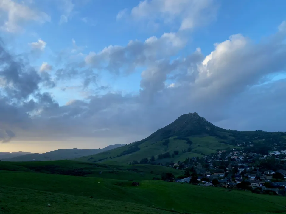 Volcanic peak and green slopes under a cloudy evening sky