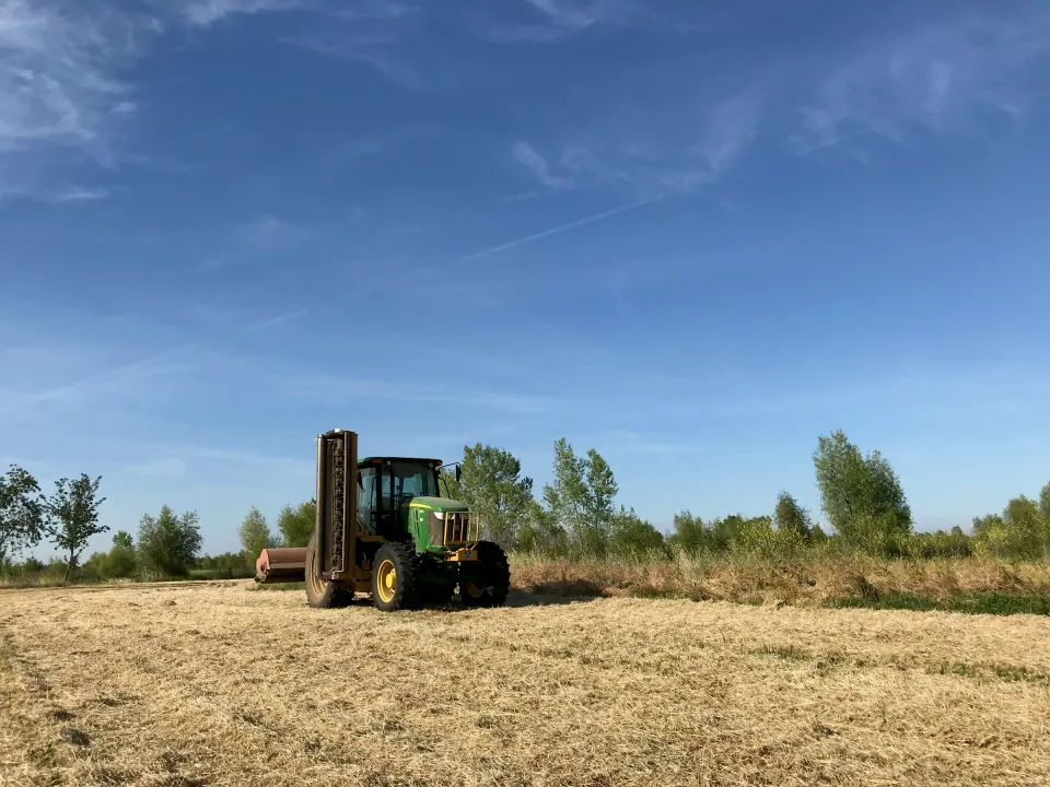 Green tractor in a cut hay field