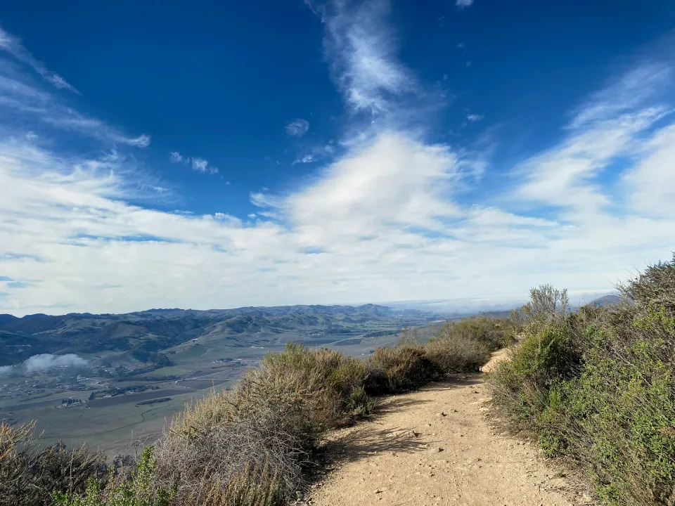 Ridge trail high above the valley under feathered clouds