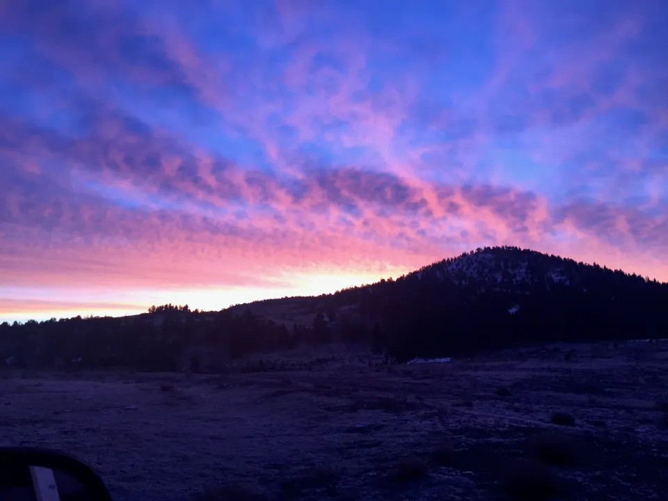 Vivid pink and purple sky over dark mountain ridge at dawn