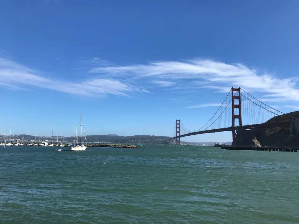 Golden Gate Bridge across blue bay with wispy clouds
